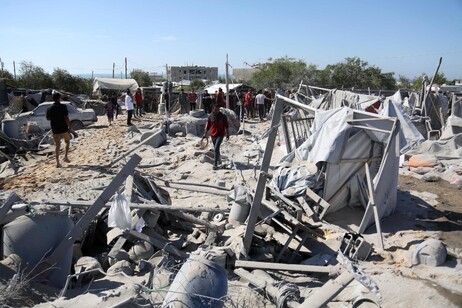 Palestinians assess the damage at a camp for displaced Palestinians in northern Khan Yunis