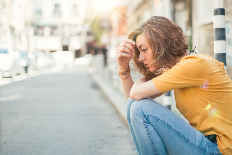 Una donna triste in strada foto iStock. - RIPRODUZIONE RISERVATA
