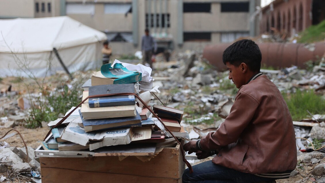 Palestinesi sfollati raccolgono libri dall'università distrutta per bruciarli e cucinare cibo