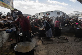 Displaced Palestinians collect donated food in Khan Yunis, southern Gaza