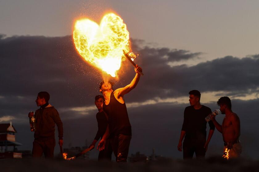 Giovani palestinesi mangiafuoco lungo la spiaggia di Gaza City, 13 gennaio 2023 © ANSA/AFP