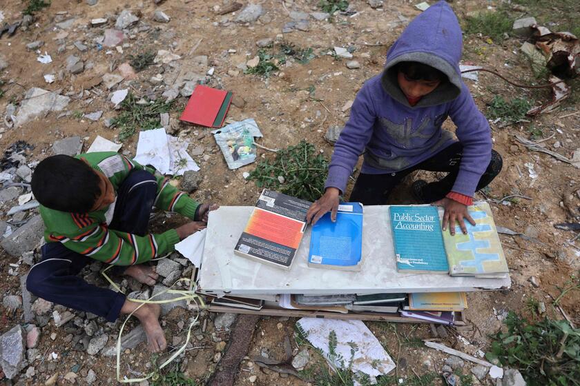 Palestinesi sfollati raccolgono libri dall'università distrutta per bruciarli e cucinare cibo