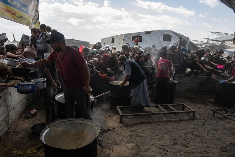Displaced Palestinians collect donated food in Khan Yunis, southern Gaza © ANSA/EPA